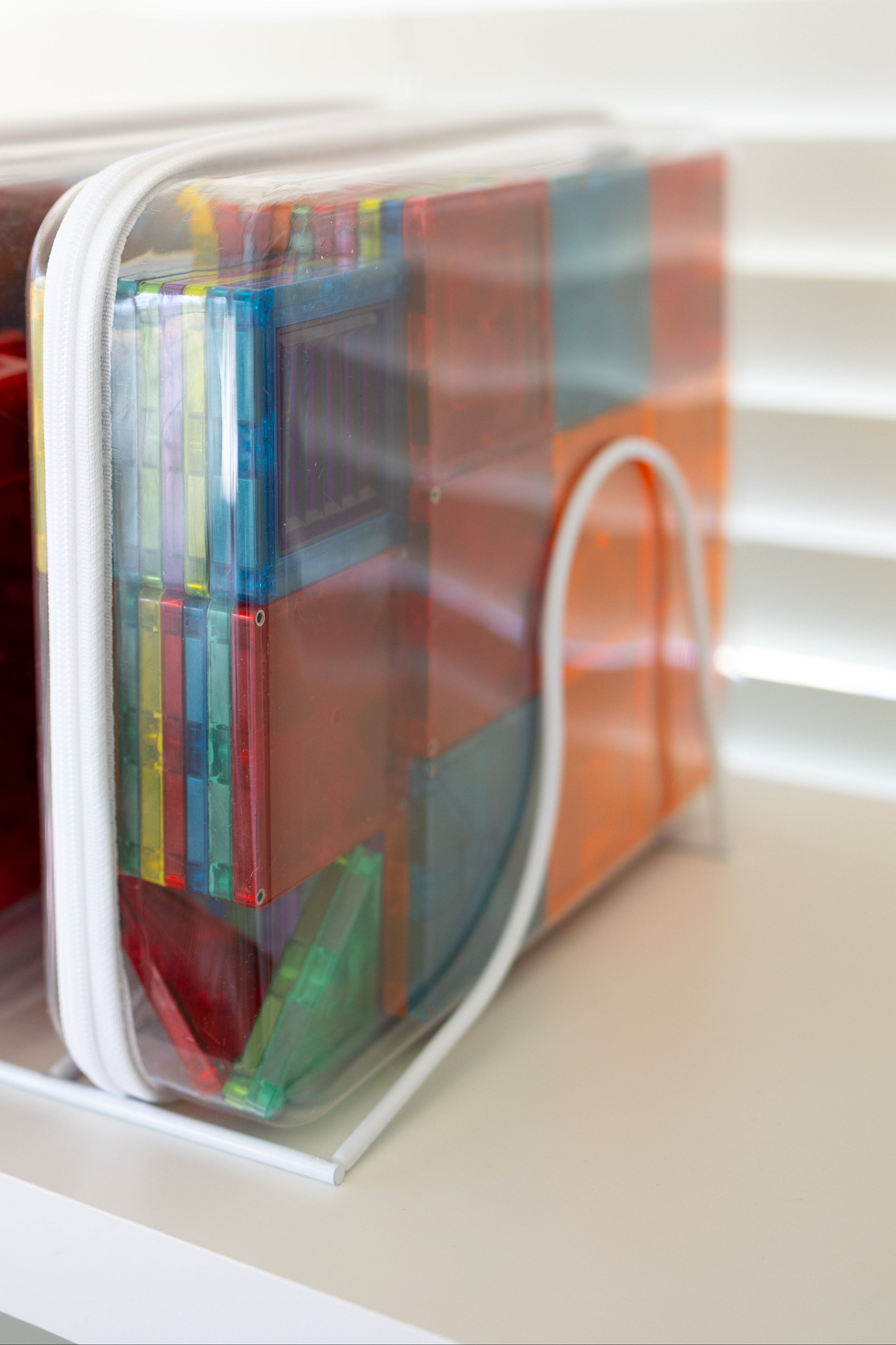 Colorful books in transparent plastic covers on a white shelf.