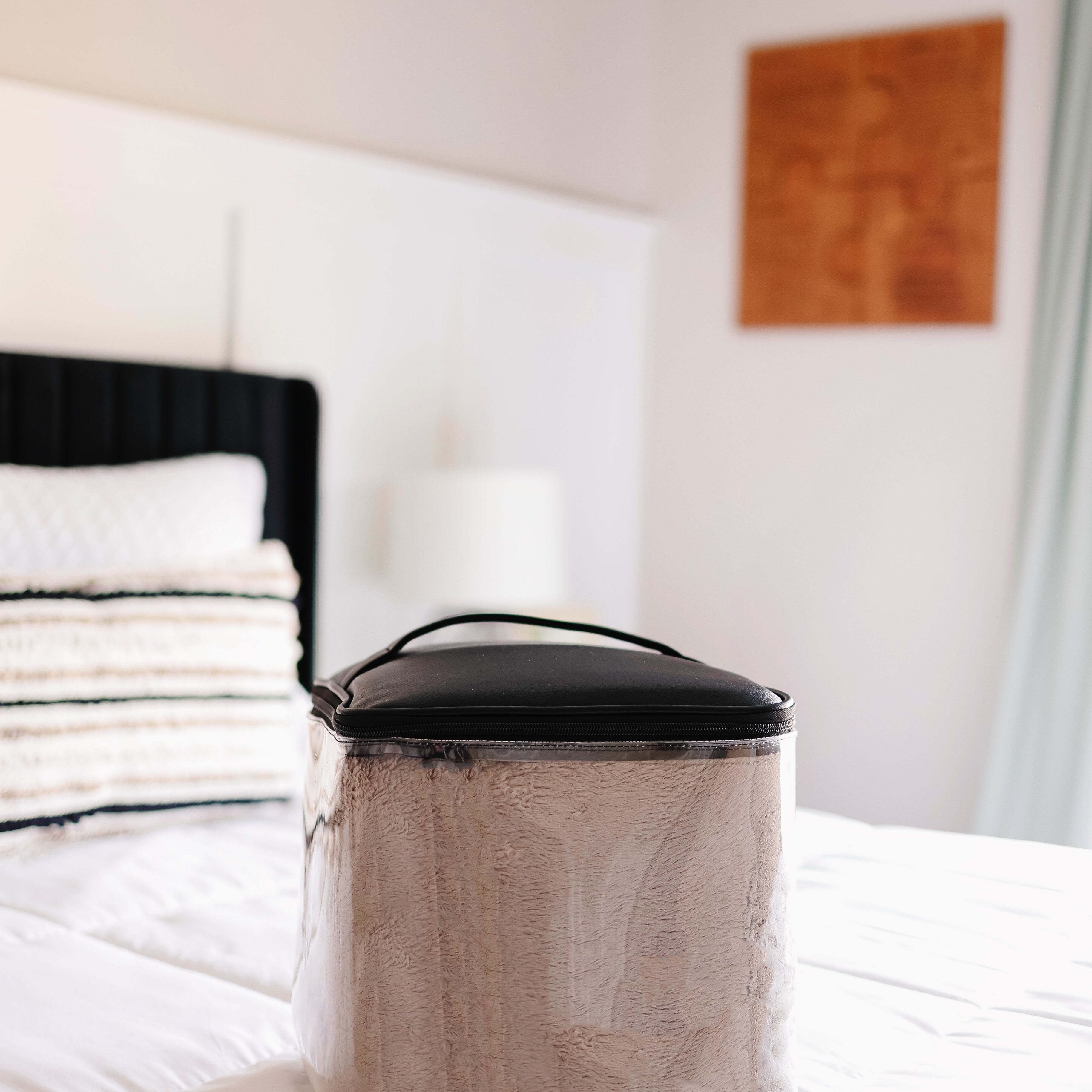 Silver trash can with black lid on a bed in a bedroom setting