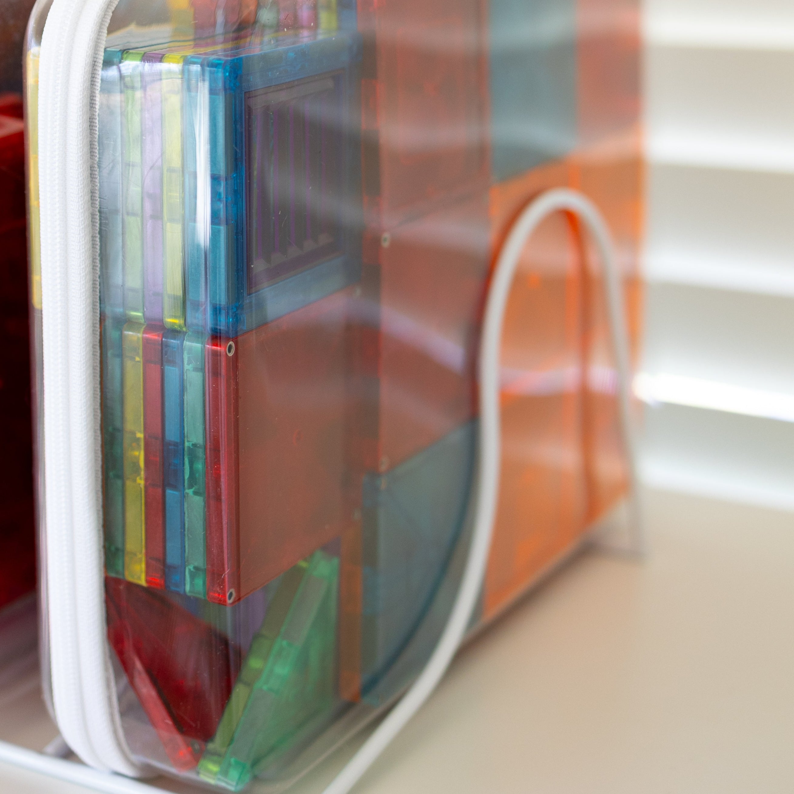 Colorful books in transparent plastic covers on a white shelf.